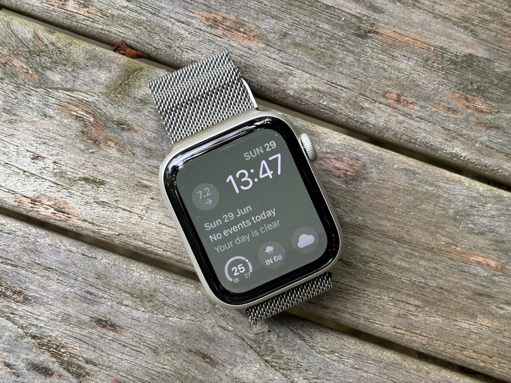 Elegant Apple Watch with a sleek, modern design on a weathered wooden surface, showcasing digital time, date, and weather information, highlighting wearable technology and health tracking features.